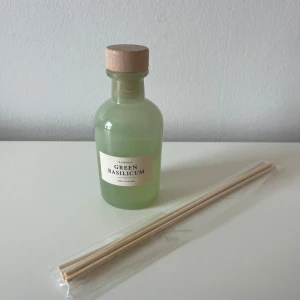 Green Basilicum doftdiffuser - Fräsch doftdiffuser med basilika-arom i en ljusgrön glasflaska med träkork. Medföljer flera tunna träpinnar för att sprida doften. 