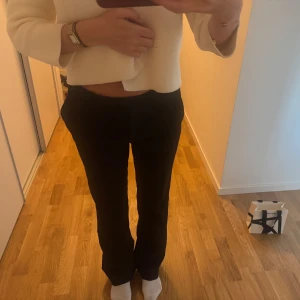 Svarta kostymbyxor med rak passform - Säljer ett par svarta kostymbyxor med klassisk rak passform och midwaist. Byxorna har diskreta fickor och stilren look, perfekta för en clean och snygg outfit. Materialet känns mjukt och följsamt, vilket gör dem riktigt bekväma att bära.