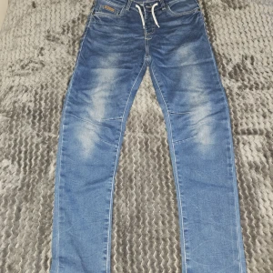 Blå relaxed fit jeans LAB Industries - Snygga blå jeans från LAB Industries i relaxed fit-modell. Jeansen har dragsko i midjan, klassiska fickor fram och bak samt ljusa slitningar för en cool look. Tillverkade i mjukt denim-material som är skönt att bära hela dagen.