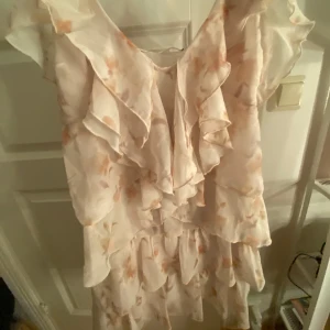 Ljus blommig volangklänning XS - Säljer en superfin kortklänning i ljusa toner med blommigt mönster och volanger. Helt nyskcik. Pris kan alltid diskuteras vid snabb affär!💕