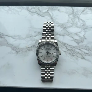Seiko DATEJUST  - Stilren Seiko DATEJUST OYSTER PERPETUAL klocka med jubilee-länk och räfflad bezel.   Tavlan/visaren har LUME alltså lysmassa vilken gör den lyser upp vilket är unikt och en ”Must have” . NH35 urverk vilket är det mest pålitliga och populära modellen. Just nu är tiden inställd men bara att ställa in när ni ska använda. Inget expert på att ta bilder men vill ni ha mer info om klockan eller bilder så är det bara att fråga! Nyttskick!!