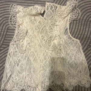 Vit spetsblus med volangdetaljer - Superfin vit blus i spets med snygga volangdetaljer vid axlarna.  Från Zara och är använd 2 gånger. Fint skick! 