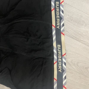 Svarta Burberry kalsonger med logoband - Svarta kalsonger från Burberry med elastiskt midjeband i beige, grått och rött med Burberry-logga runtom. Kalsongerna är i mjukt material och har en klassisk, stilren look med snygga kontrastdetaljer i midjan.
