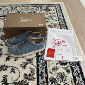 Blå mockasneakers från Christian Louboutin - Byten funkar super bra med. Snygga blå sneakers i mocka från Christian Louboutin med klassisk röd sula. Skorna har rund tå, platt sula och grå snörning. Kommer med originalkartong, dustbag och äkthetskort. Perfekta för dig som vill sticka ut med exklusiva detaljer. Och priset kan diskuteras.