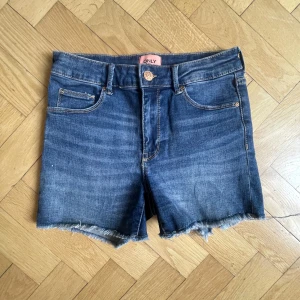 Blå jeansshorts från ONLY - Snygga blå jeansshorts från ONLY. Shortsen har normal passform och är perfekta för sommaren. De har en knapp och kedja framtill.💕