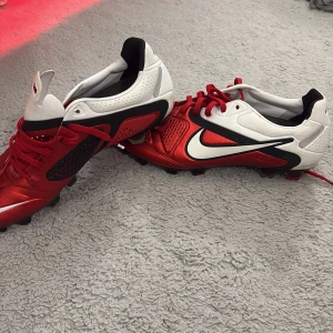 Nike fotbollsskor röd/vit Kanga-Lite - Snygga fotbollsskor från Nike i rött och vitt med svarta detaljer och stor vit Swoosh. Ovandelen är tillverkad i Kanga-Lite syntetmaterial för bra känsla och passform. Skorna tillverkas då inte längre och är sällsynta därav priset. Priset går att diskutera