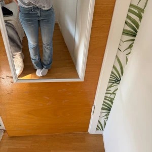 Blå bootcut jeans med normal midja - Säljer ett par klassiska blå jeans med bootcut-modell och normal midja. Jeansen har en snygg tvätt och sitter tajt upptill med utsvängda ben. Perfekta till sneakers eller boots och passar till många olika stilar.