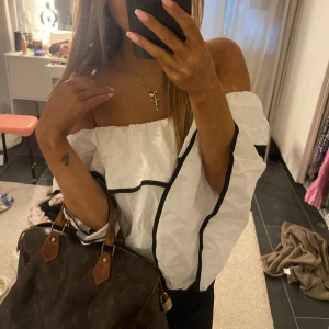 Vit off shoulder blus med svarta detaljer och utsvängda armar - Vit off shoulder blus med svarta detaljer och utsvängda armar