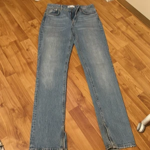 Blå raka jeans från Zara, strl 36 - Snygga ljusblå jeans från Zara i klassisk rak modell med slits nere. Jeansen har fem fickor, normalhög midja och är tillverkade i ett mjukt bomullsjeanstyg. Perfekta till sneakers eller boots för en chill look.