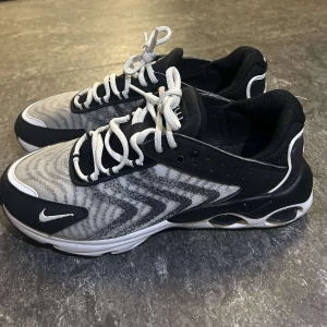 Nike Air sneakers svart/vit mönster - Nike Air sneakers i svart och vitt med coolt vågigt mönster på ovandelen. Skorna har vit snörning, svart mesh och detaljer i syntet. Sulan har synliga luftbubblor och tydlig Nike-logga bak och fram. Perfekta för dig som gillar sportig och modern stil. Orginal pris - 1 500 kr