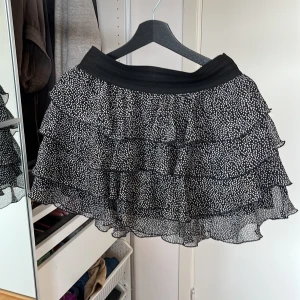 Svartvit volangkjol från Yessica - Supersöt kort volangkjol från Yessica i svart med vita prickar. Kjolen har flera lager volanger som ger en riktigt flowy känsla och bred resår i midjan för extra komfort. DMa för mer info 🩷