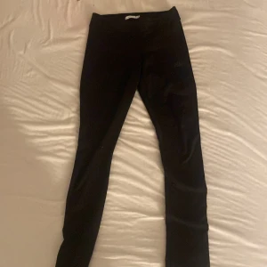Svarta leggings i stretchigt material - Svarta leggings med tight passform och hög midja. Tillverkade i ett stretchigt och mjukt material som sitter skönt mot kroppen. Perfekta för träning eller chill dagar.