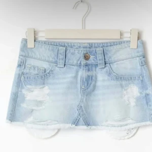 Populär jeanskjol från Gina Tricot Young 14+ - Trendig ljusblå jeanskjol i kort modell med slitna detaljer och rå kant nertill. Klassisk femficksdesign och bälteshällor. Perfekt för dig som gillar en avslappnad och cool stil.