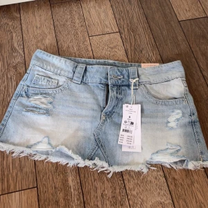 Ljusblå jeanskjol med slitningar - Trendig ljusblå jeanskjol från gina tricot 14+ med slitna detaljer och fransig nederkant. Den är helt ny och oanvänd men passade tyvärr inte mig. Den är även helt slutsåld