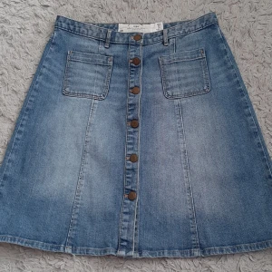 Blå jeanskjol från L.O.G.G. H&M - Snygg blå jeanskjol från L.O.G.G. H&M i A-linjeform med knappar framtill och två stora fickor. Kjolen har bälteshällor och klassisk denimlook, perfekt till sneakers eller boots. Modellen är kort och har en avslappnad vibe.