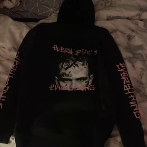 Svart Lil Peep hoodie med tryck - Svart hoodie med stor huva och tryck av Lil Peep på både fram- och baksidan. Rosa text på ärmarna och bröstet. Jätteskön och älskar den! använder den inte för att jag ej lyssna på han längre och känner då att ja inte vill ha hoodies kvar. har även fler Hoodies av han så är ni intresserade skriv för bilder på dom oxå. pris kan även diskuteras❣️