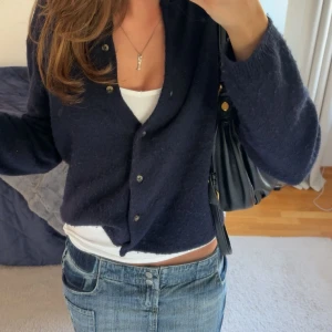 Jeanskjol från QOO.G med fickor - Säljer en blå jeanskjol från QOO.G med coola detaljer som stora fickor både fram och bak samt dubbla knappar i midjan. Kjolen är kort och har en klassisk denimlook med slitningar och patchade detaljer. Midja: 38 cm rakt över, höft: 44 cm rakt över och längd: ca 30 cm. Köpt i London, använd max 1 gång.