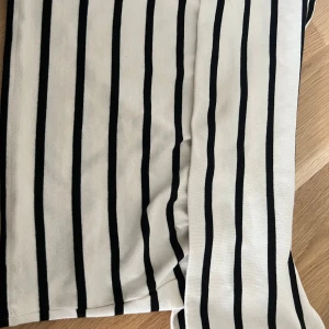 Randig offshoulder topp från Gina Tricot - Snygg offshoulder topp från Gina Tricot i beige med svarta vertikala ränder. Toppen är i mjuk bomull.