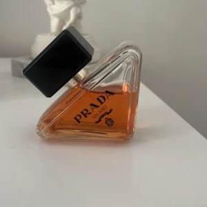 Prada Paradoxe Intense Eau de Parfum - Prada Paradoxe Intense Eau de Parfum i en unik, trekantig glasflaska med svart, rektangulär kork. Doften har en varm bärnstensfärgad vätska och flaskan är elegant med tydlig Prada-logga och Milano-detaljer. Perfekt för dig som gillar lyxiga och trendiga parfymer. Den är knappt använd och är i mycket bra skick. Har tyvärr inte kartongen kvar.