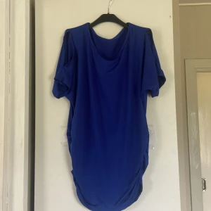 Kornblå kortklänning med slitsade ärmar - En kornblå kortklänning med rund halsringning och coola slitsade detaljer på ärmarna. Klänningen har en loose passform och är tillverkad i ett mjukt, stretchigt material som känns skönt mot huden. Perfekt för dig som gillar en enkel men ändå unik look.