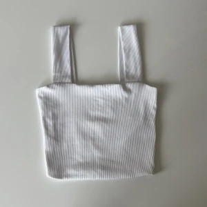 Vit ribbad linnetopp - Snygg vit ribbad linnetopp med breda axelband och croppad passform. Toppen är använd ca 5 gånger och är som ny.