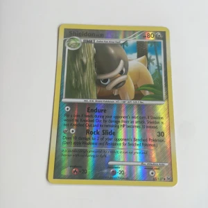 Pokémonkort: Shieldon & Igglybuff (holo) - Två coola Pokémonkort med holoeffekt: Shieldon och Igglybuff! Perfekt för dig som samlar eller vill boosta din lek med unika och glänsande kort. Färgstarka motiv och klassisk Pokémonkänsla – ett måste för fans!