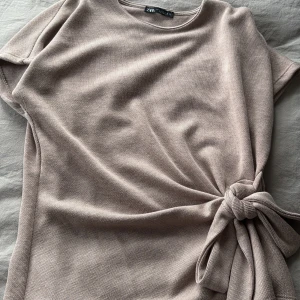 Beige stickad topp med knyt från Zara - Superfin beige stickad topp från Zara med kort ärm och snygg knytning i sidan. 💘💘
