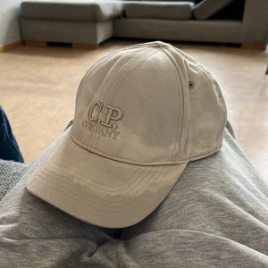 CP Company keps - Snygg beige keps från cp company.                       Kepsen har små defekter på framsidan som möjligtvis kan tas bort. Pris kan diskuteras