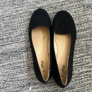 Svarta ballerinaskor från Alley - Klassiska svarta ballerinaskor från Alley i storlek 39 som aldrig har använts. Skorna har rund tå, platt sula och är gjorda i ett mjukt material som liknar mocka. Perfekta för dig som gillar en enkel och stilren look.