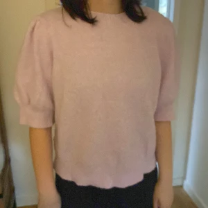 Ljuslila stickad tröja från Vero Moda - Superfin ljuslila stickad tröja från Vero Moda med puffiga halvlånga ärmar och rund halsringning. Tröjan har en mjuk och mysig känsla, perfekt för dig som gillar en söt och trendig look. Passar snyggt till både jeans och kjol.