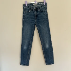 Blå slim fit jeans från Dobber - Snygga blå jeans från Dobber, modellen The Teacher. Jeansen har midja i midwaist, smal passform och klassisk femficksdesign. Materialet är jeans i bomull med lätt tvättad look och subtila slitningar. Perfekta för en stilren och avslappnad vibe.