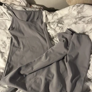 Ljusgrå långklänning från 157 - Supersnygg ljusgrå långklänning från 157 med smala axelband och enkel, stilren design. Klänningen har en rak passform och är tillverkad i ett mjukt, slätt material som känns skönt mot huden. Perfekt för dig som gillar minimalistisk stil . Andvänd en gång på pappas bröllop men ingen mer gång 