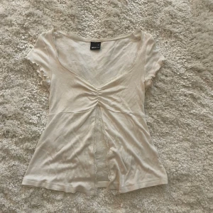 Vit topp från Gina Tricot XS - Supersöt vit topp från Gina Tricot med v-ringning och rynkdetalj framtill. Korta ärmar med volangkant och spets längs halsringningen. Perfekt för dig som gillar romantiska och feminina vibes💕