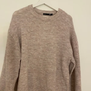 Beige stickad tröja från 157 - Mysig beige stickad tröja från 157 med rund halsringning och lång ärm. Den är ganska lång.