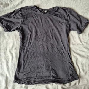 Svart t-shirt från Impuls, storlek M - En basic svart t-shirt från Impuls i storlek M. T-shirten har rund halsringning och korta ärmar, perfekt till jeans eller shorts. Tillverkad i mjukt material som känns skönt mot huden. Enkel och stilren design utan tryck eller mönster.