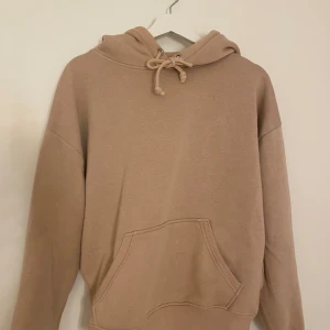 Beige hoodie från BikBok med huva - Säljer en beige hoodie från BikBok i storlek XS. Tröjan har huva med snörning och en stor magficka framtill.