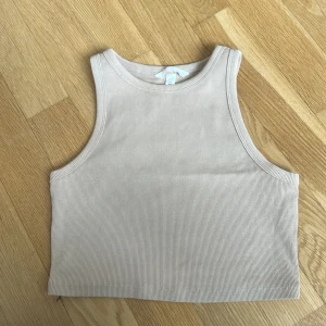 Beige ribbad linnetopp från H&M - Säljer en beige ribbad linnetopp från H&M i storlek M. Toppen är ärmlös med rund halsringning och croppad passform. Skickas på post eller hämtas i Östersund. Nypris 149kr.