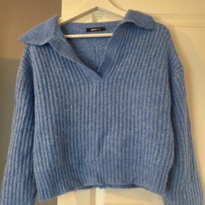 Blå stickad tröja från Gina Tricot - Superfin blå stickad tröja från Gina Tricot med krage och v-ringning. Säljer pågrund av att den aldrig kommit till användning Snygg till både jeans och kjol!