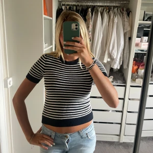 Randig croppad stickad topp - Säljer en svartvit randig croppad stickad topp med korta ärmar och rund hals. Tjockare ribbade muddar vid ärmslut, hals och nederkant. Xxs i storleken men passar s/m