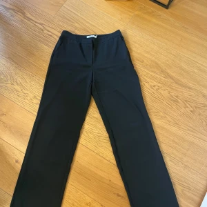 Svarta kostymbyxor raka ben - Klassiska svarta kostymbyxor från NA-KD med raka ben och diskret midja. Snygg passform och stilren look, perfekta till en dressad outfit. Byxorna har fickor i sidorna och är gjorda i ett mjukt material som känns bekvämt hela dagen.