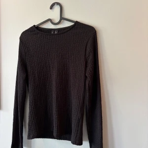 Svart långärmad tröja vero mods - En svart långärmad tröja från vero moda med strukturerad, rutmönstrad yta. Tröjan har en rak passform och rund halsringning, perfekt för lager-på-lager. Enkel och stilren design som funkar till det mesta.