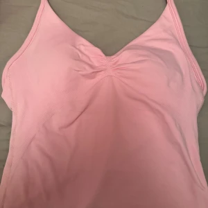 Ljusrosa strappy linnetopp - Supersnygg ljusrosa linnetopp med smala axelband och v-ringning. Toppen är lång i modellen och har en lätt rynkad detalj vid bysten. Perfekt för träning eller chill dagar. Storlek xs säljer för vill köpa en annan färg den är som ny. Kan skicka bild att de är äkta 