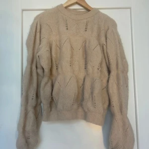 Beige stickad tröja & Other Stories - Superfin beige stickad tröja från & Other Stories med unikt hålmönster och ribbade muddar. Tröjan har en rund halsringning och långa ärmar, perfekt för lager på lager under kyliga dagar. Snygg att styla med jeans eller kjol för en trendig look.