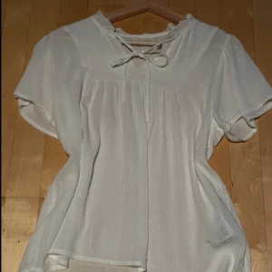 Söt vit blus - Söt vit blus med vita prickar (se bild 3), storlek 36 men passar 34 med. Näst intill helt ny, endast använd 2 ggr. Köpt för ca 300, mitt pris 200 kr🌸