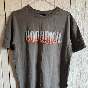 Grå T-shirt från Hoodrich - Jag säljer en grå t-shirt från Hoodrich. Den har en del detaljer som man kan se på bilderna. Har använts en del, men sparsamt! På bilderna är den något skrynklig, men kan stryka den innan den skickas. Passformen är normal, storlek S. 