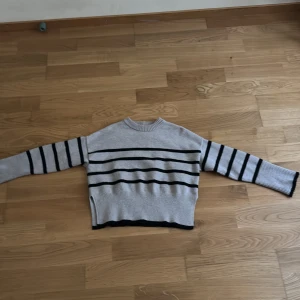 Grå randig stickad tröja Bershka - Säljer en stickad tröja från Bershka i storlek XS. Tröjan har svarta horisontella ränder över hela kroppen och ärmarna, samt ribbade muddar och nederkant. Perfekt för dig som gillar en chill och stilren look.