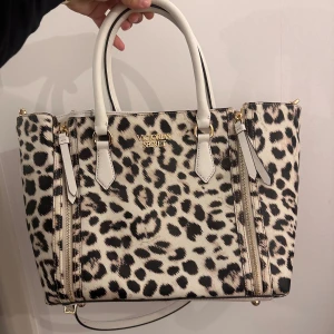 Victoria's Secret Väska - Snygg handväska från Victoria's Secret i äkta skinn med leopardmönster och vita detaljer. Väskan är aldrig använd så den är som ny. 