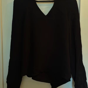 Svart blus från Tiger of Sweden - Säljer en svart blus från Tiger of Sweden med v-ringning och långa ärmar. Blusen har en stilren och enkel design. Storlek 36.