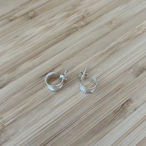 Silvriga  hoops örhängen💗💗 - Säljer ett par stilrena silvriga hoops med snygg design. De är runda och blanka, perfekta för dig som gillar minimalistiska smycken med lite edge. Passar till allt och är lätta att bära varje dag. De är endast testade och är i sterling silver!!💗