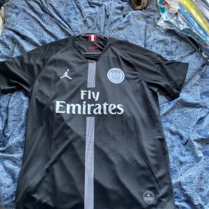 PSG Neymar Jr svart matchtröja XL - Svart PSG fotbollströja i samarbete med Jordan, Neymar Jr 10 på ryggen. Klassisk design med Fly Emirates-tryck, PSG-emblem och vit rand framtill. Tröjan är i helt nyskick lappar sitter kvar. Storleken är XL och passar någon som är 180-185 cm lång. Vid minsta fundering fråga.